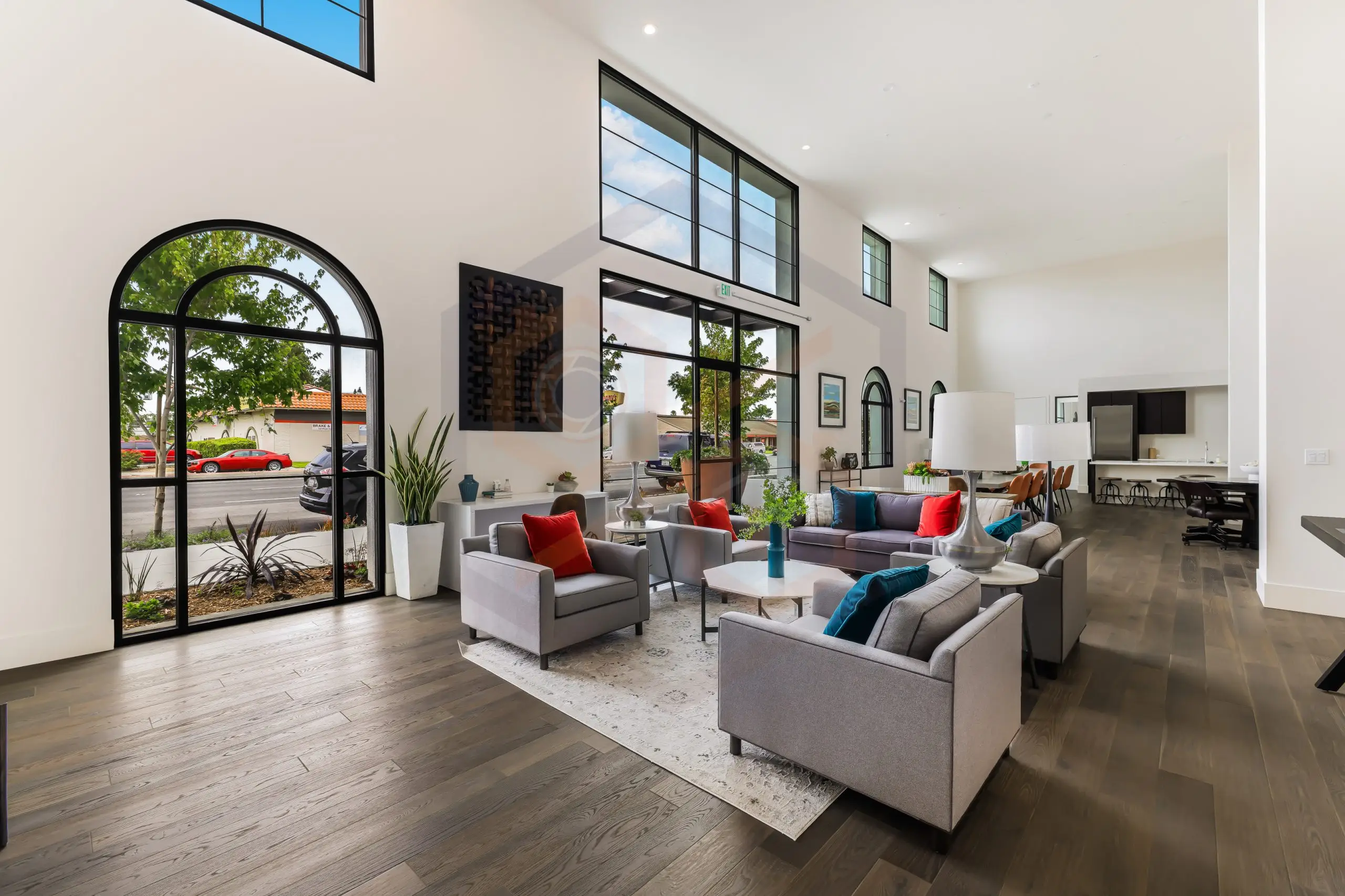 Bright modern living room with arched windows, high ceilings, gray sofas.